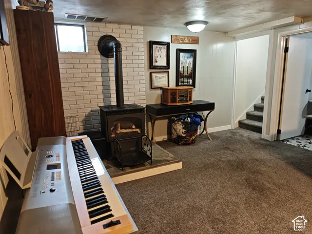 Freestanding wood-burning stove with a metal chimney flue, anchored by a white brick accent wall and a stone hearth