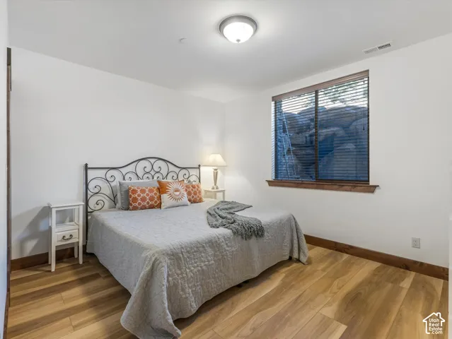 Bedroom featuring wood-finish flooring, dark wood trim, and a window with a rock formation backdrop