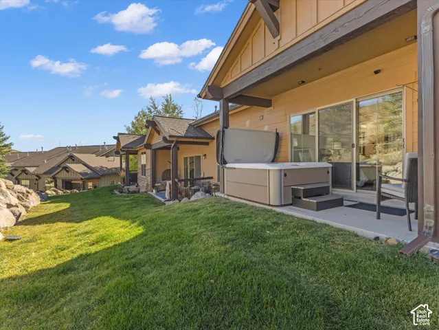 Covered patio featuring a concrete slab foundation, an integrated hot tub, sliding glass doors, and exposed wooden support beams
