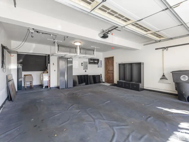 Spacious multi-car garage featuring overhead storage racks, an automatic garage door opener, finished wall surfaces, and a wood-finish interior door