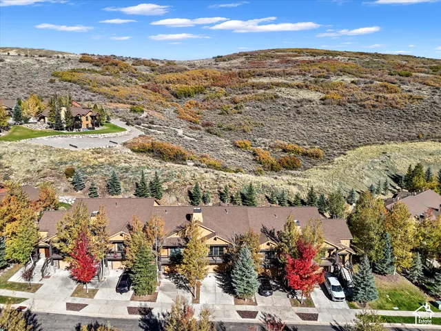 Multi-unit residential complex featuring gabled rooflines, concrete driveways, and surrounding mountainous terrain with mature deciduous and evergreen trees