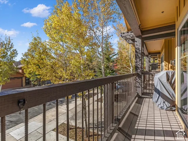 Covered balcony featuring wood-plank flooring, dark-finished timber railings, and vertical metal balusters