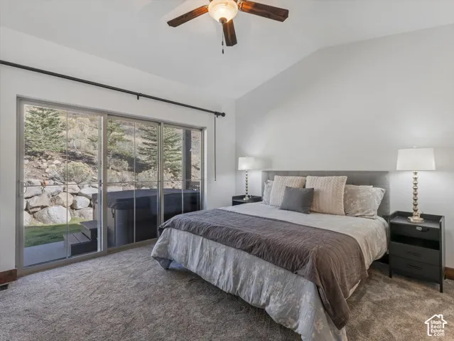 Vaulted ceiling featuring a central lighted ceiling fan, expansive sliding glass doors, and wall-to-wall carpeting