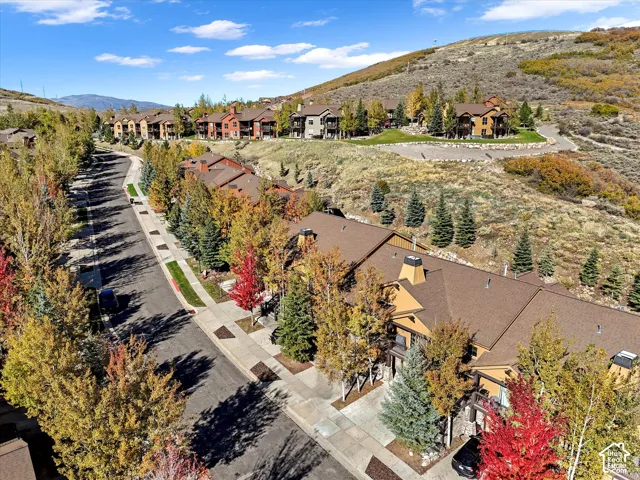 Aerial view of residential structures featuring multi-story designs with stone and wood-finish siding, asphalt shingle roofing, paved streets, and mature tree landscaping