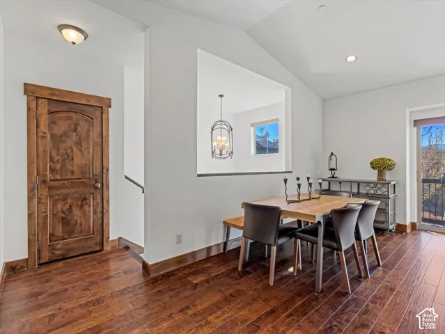 Wood-finish flooring, vaulted ceilings, solid wood interior door with rustic trim, recessed lighting, and glass-panel exterior door