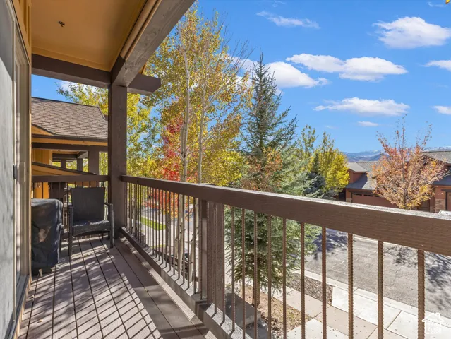 Covered balcony featuring wood-finish decking, dark-stained timber framing, and a metal balustrade with horizontal support rails