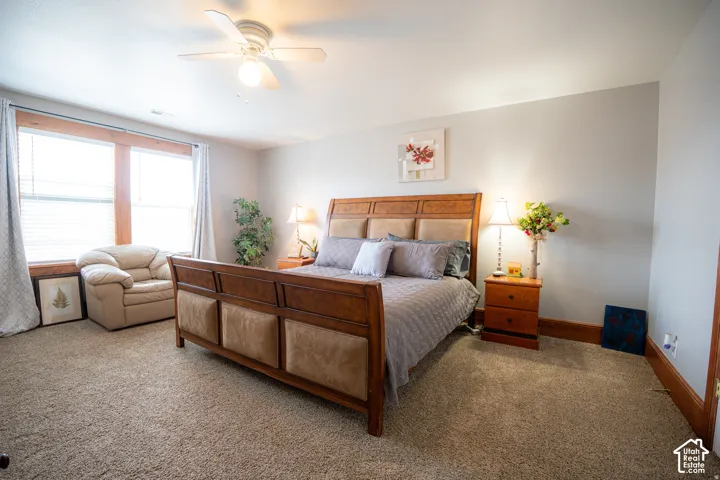 Neutral-toned interior featuring wall-to-wall carpeting, wood-trimmed windows, and a ceiling-mounted light fixture with integrated fan