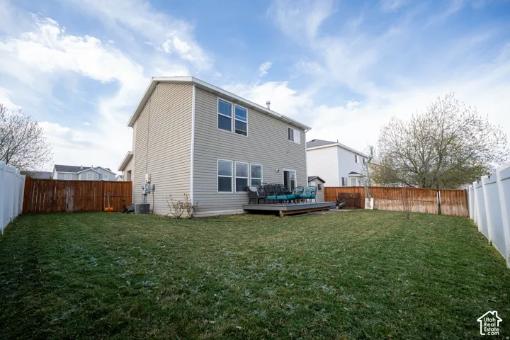 Rear exterior featuring horizontal vinyl siding, multi-level wood deck, and enclosed yard with a combination of white vinyl and wood privacy fencing