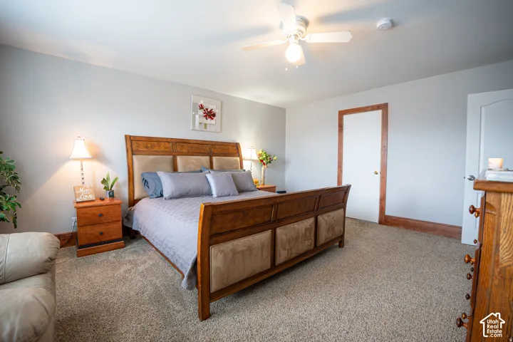 Neutral-toned room featuring wall-to-wall carpeting, wood-finish door and trim detailing, and a ceiling-mounted light fixture with a fan