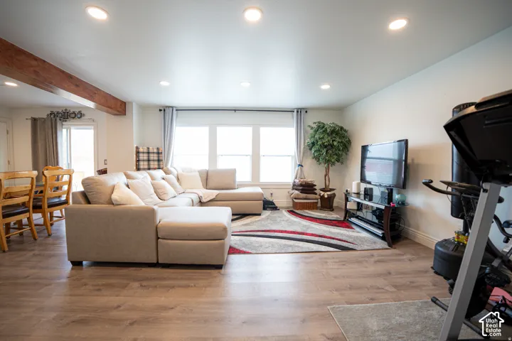 Open-concept living space featuring wood-finish flooring, recessed lighting, and a prominent wood-finished structural support beam
