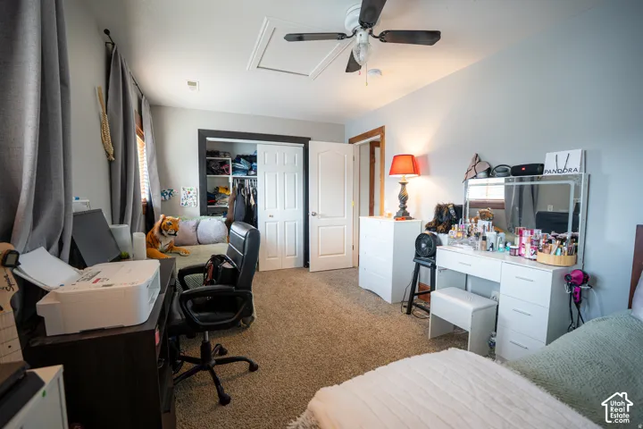 Neutral-toned interior featuring wall-to-wall carpeting, a ceiling fan with light fixture, and a built-in closet with double-panel doors