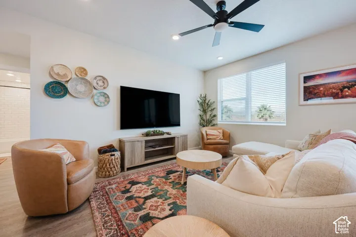 Living area featuring recessed lighting, a matte black ceiling fan, and wood-finish flooring