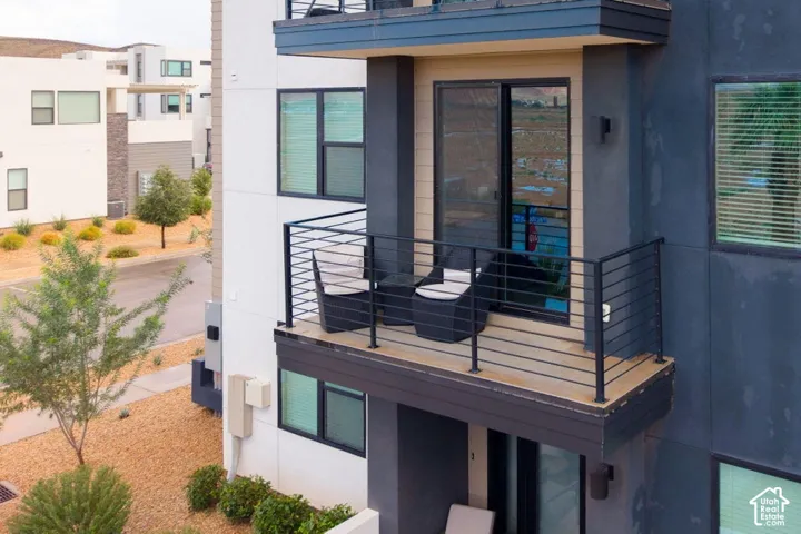 Private balcony featuring horizontal cable railing, composite decking, and sliding glass door entry