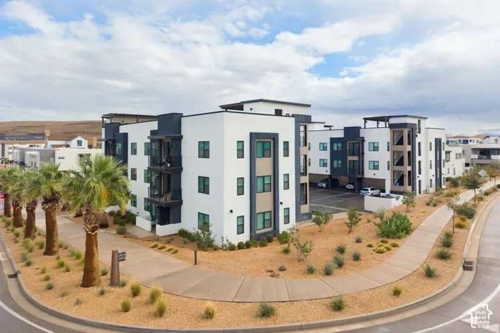 Modern multi-story structure featuring a smooth stucco exterior with contrasting architectural trim, private balcony spaces, and dedicated ground-level covered parking