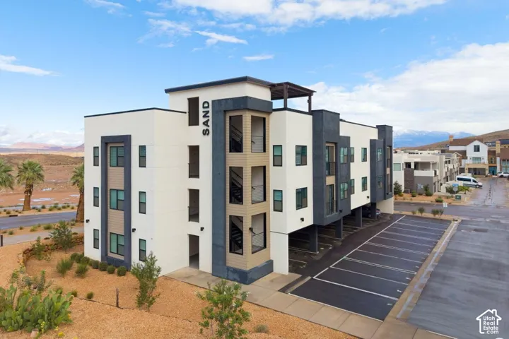 Multi-level exterior featuring a combination of stucco and wood-finish siding, flat roofline, covered parking area, and an upper-level pergola