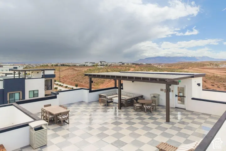 Rooftop terrace featuring a checkered tile floor, pergola, and perimeter masonry walls