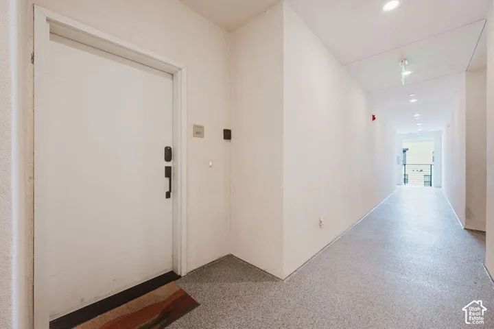 Entryway featuring a solid panel door, electronic deadbolt hardware, recessed ceiling lighting, and neutral-tone flooring