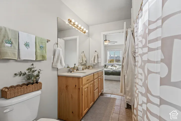 Bathroom featuring a wood vanity with a solid-surface countertop, a large wall-mounted mirror, a multi-bulb vanity light fixture, and tile flooring