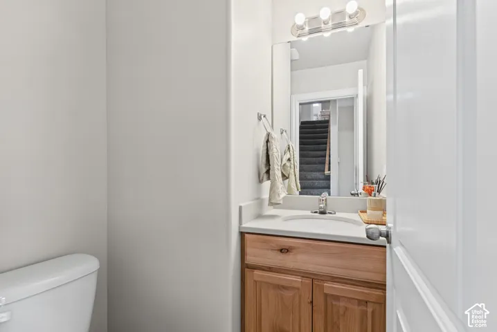 Natural wood-finish vanity with a stone-composite countertop, integrated sink, polished chrome faucet, and three-bulb vanity light fixture
