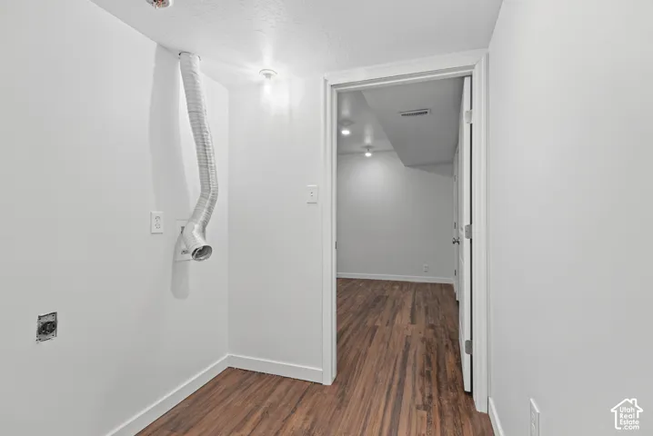 Utility space featuring wood-finish flooring, a wall-mounted dryer vent, and recessed ceiling lighting