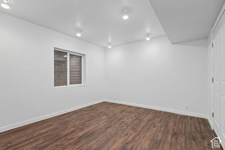 Interior room featuring wood-finish flooring, white walls, recessed ceiling lighting, and a window with horizontal blinds