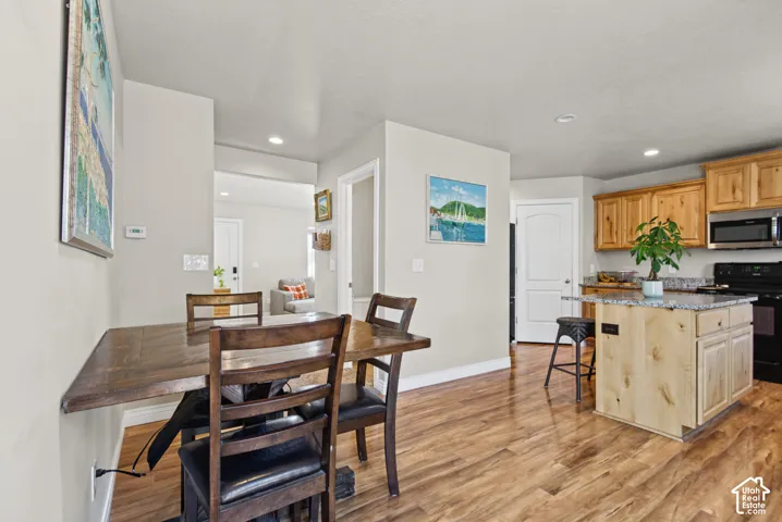 Kitchen featuring wood cabinetry, stone countertops, central island, and wood-finish flooring