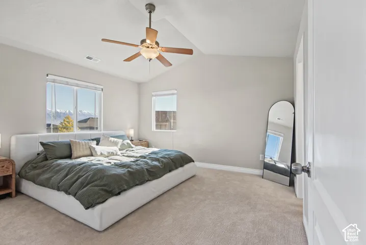 Vaulted ceilings, neutral wall tones, carpeted flooring, and a central ceiling fan featuring integrated lighting
