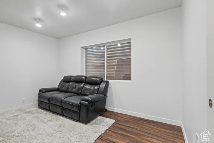 Neutral-toned interior space featuring wood-finish flooring and a window with a corrugated metal window well