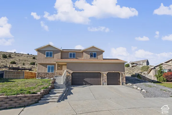 Two-story stucco exterior featuring stone veneer accents, an attached three-car garage, and concrete driveway