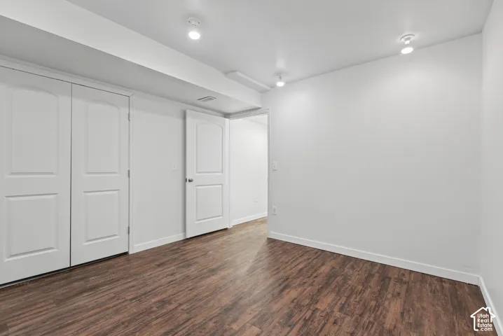 Room featuring wood-finish flooring, white walls, double-door closet, multi-panel interior door, and recessed lighting