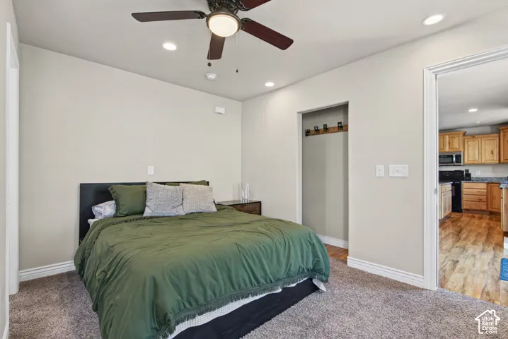 Neutral-toned interior space featuring recessed lighting, a ceiling fan with integrated light fixture, wall-mounted coat hooks, and carpeted flooring