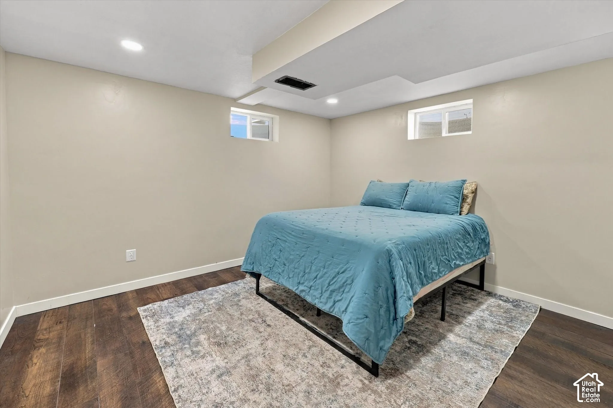 Neutral-toned walls, wood-finish flooring, and recessed ceiling lighting with dual egress windows