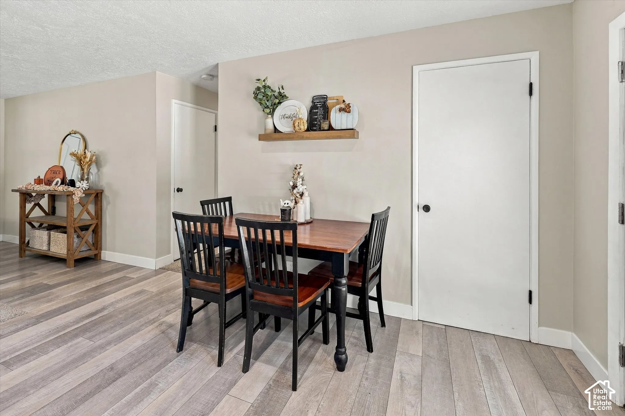 Wood-finish flooring, neutral wall tones, and a wall-mounted wood shelf