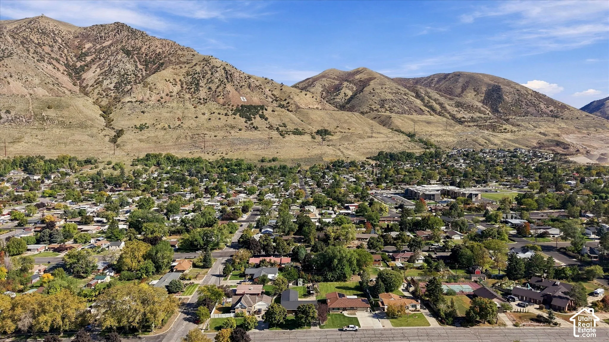 Aerial perspective of a residential neighborhood featuring established tree cover and direct proximity to a prominent mountain range