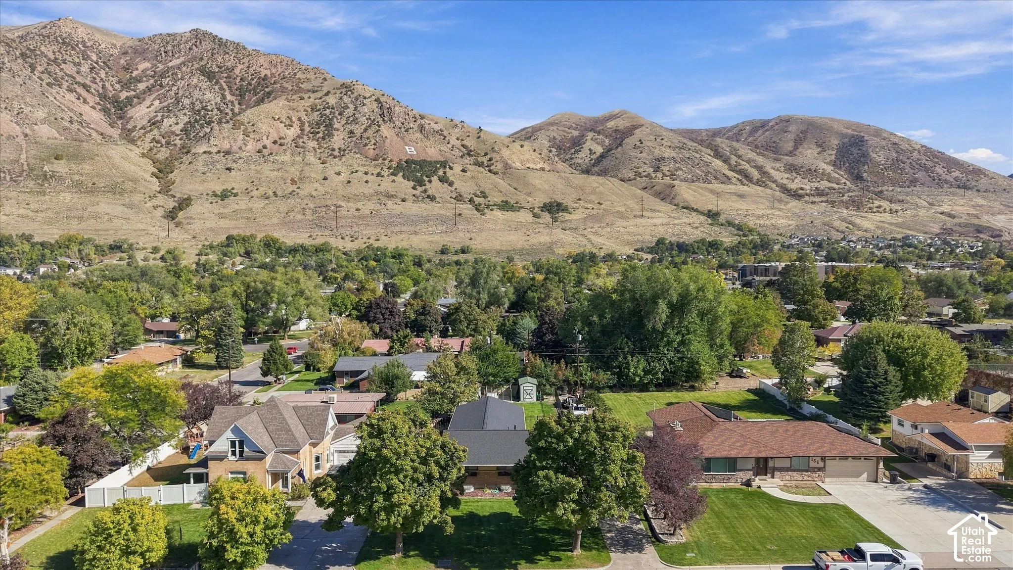 Aerial perspective featuring mountainous topography, mature trees, and landscaped residential lawns