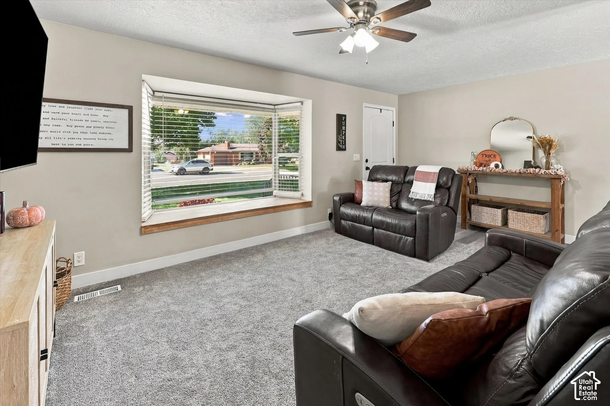 Bay window with wood trim, ceiling fan with light kit, and neutral wall-to-wall carpeting