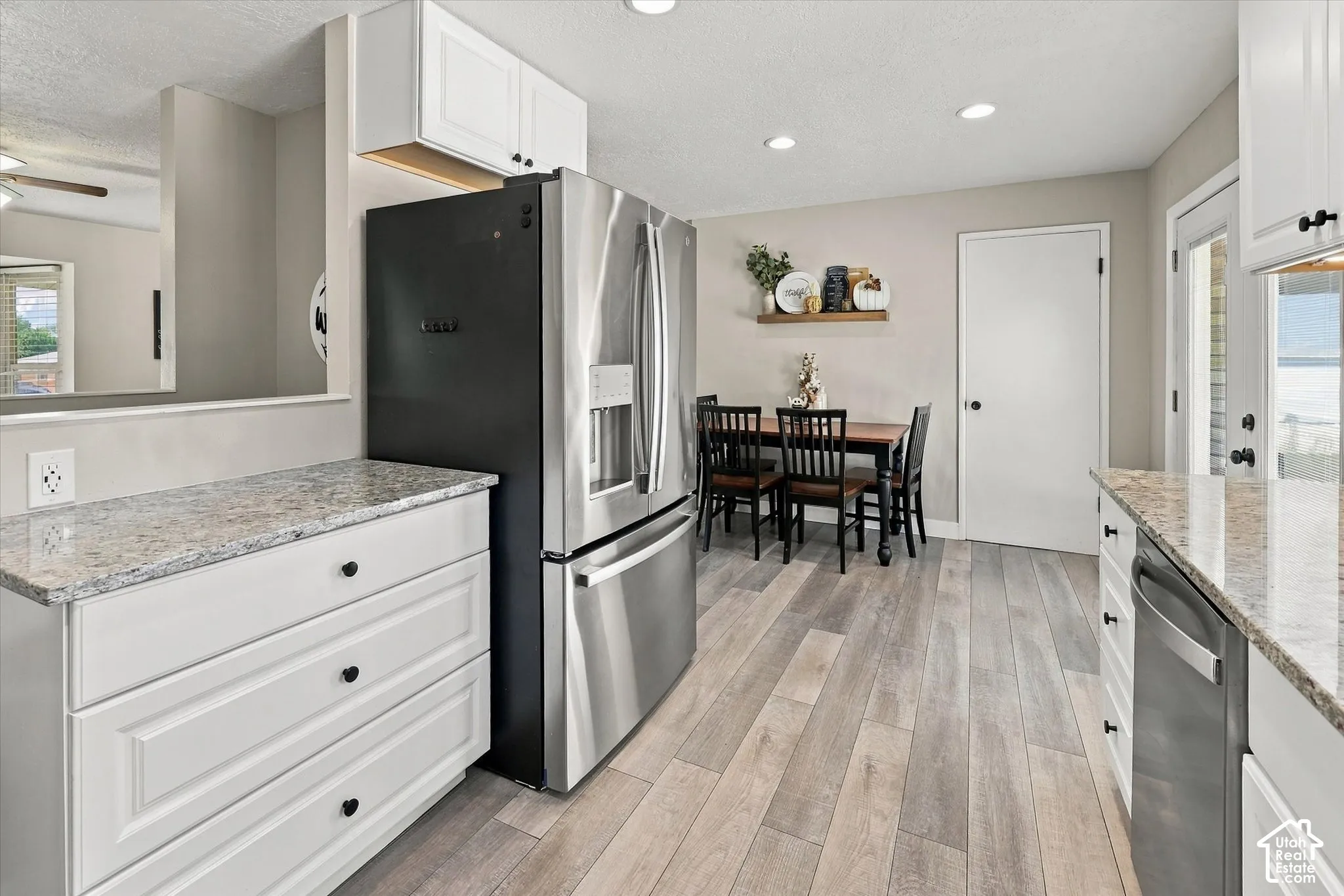 Kitchen featuring white shaker-style cabinetry, stone-finish countertops, stainless steel appliances, wood-finish flooring, and recessed ceiling lighting