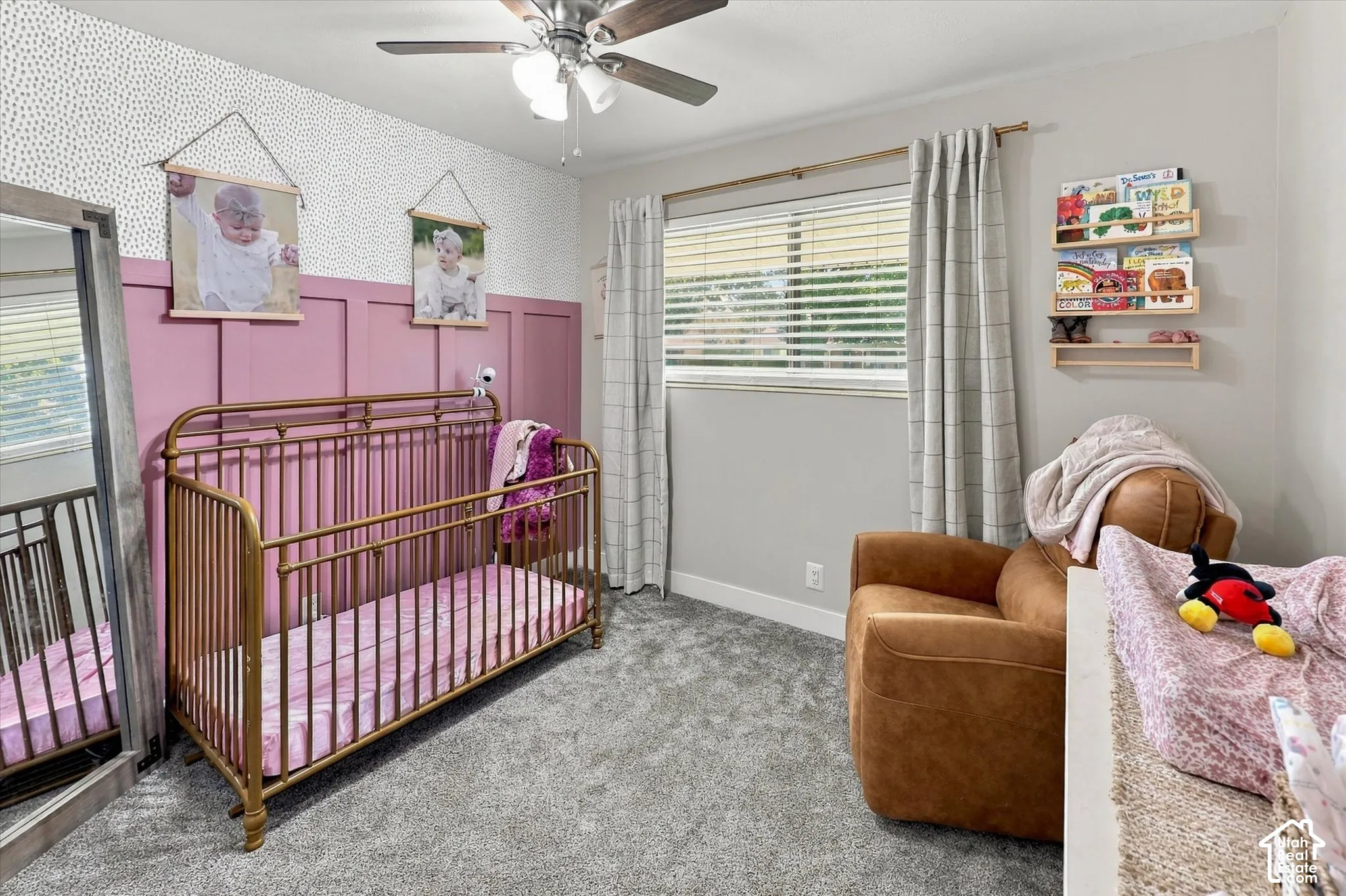 Wall-mounted paneling, patterned accent wallpaper, wall-to-wall carpeting, ceiling fan with light fixture, and built-in wall shelving