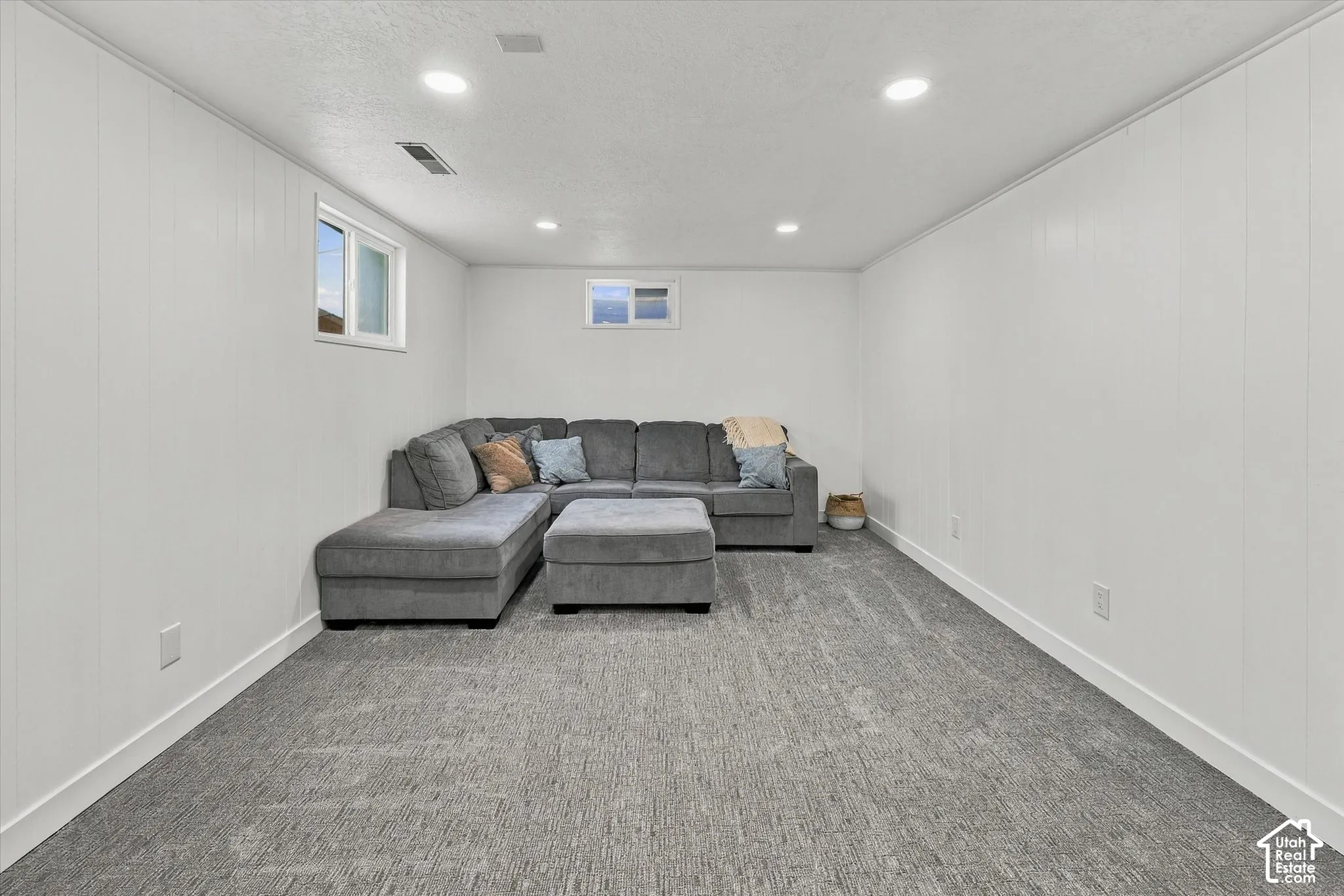 Interior room featuring neutral wall paneling, recessed lighting, carpeted flooring, and two slider windows