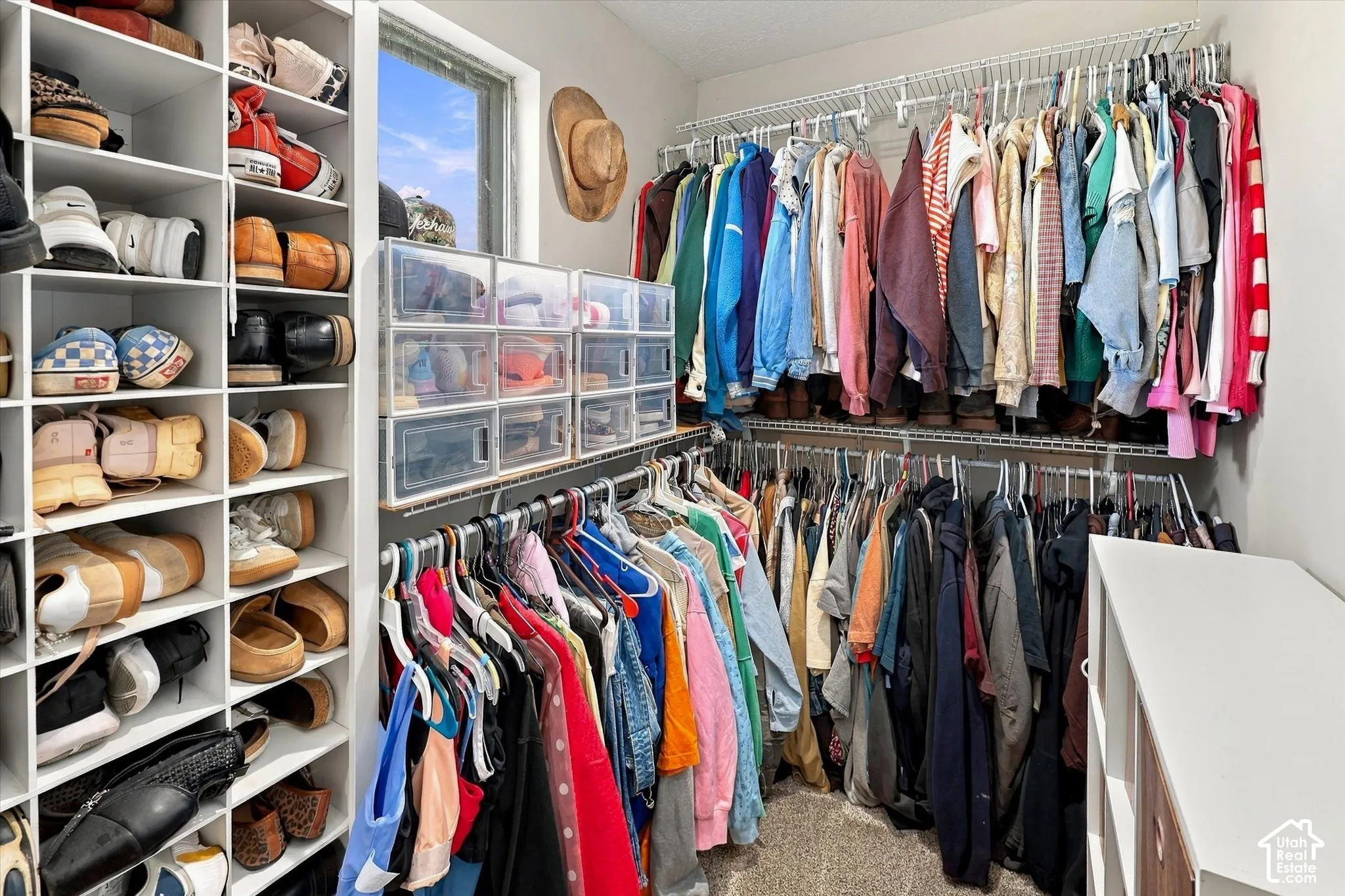 Walk-in closet featuring floor-to-ceiling custom shelving, tiered wire hanging racks, and a window