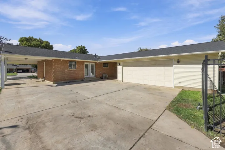Exterior featuring brick and horizontal siding, an attached two-car garage, a covered carport, and metal perimeter fencing