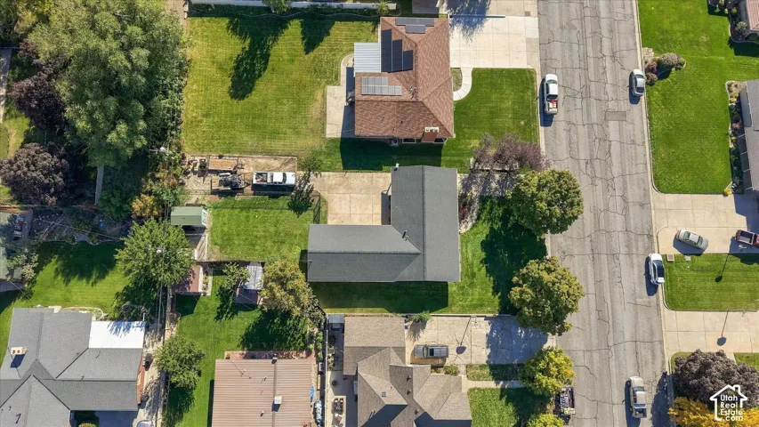 Aerial perspective of property featuring an expansive lawn, concrete driveway, and established trees
