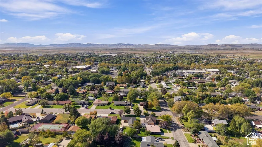 Aerial perspective of the residential area featuring mature trees, paved streets, and a mountain range backdrop