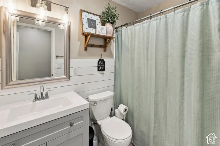 Bathroom featuring white shiplap walls, a vanity with a rectangular sink, brushed nickel hardware, and a framed vanity mirror with an attached three-light fixture