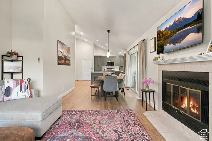 Vaulted ceilings featuring recessed lighting, stone-surround fireplace with mantle, and wood-finish flooring