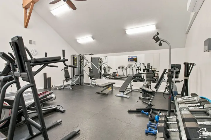 Vaulted ceiling with exposed wood-beam detailing, wall-to-wall mirrored surfacing, industrial-style rubberized flooring, and flush-mount lighting fixtures