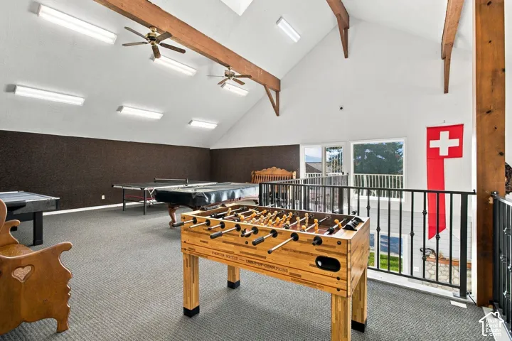Vaulted ceiling featuring exposed timber beams, recessed lighting, ceiling fans, wall-to-wall carpeting, and metal railing overlooking the lower level