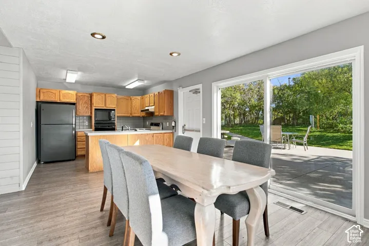 Kitchen featuring natural wood cabinetry, recessed lighting, and wood-finish flooring, complemented by sliding glass doors opening to an exterior concrete patio