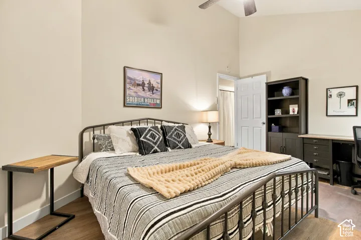 Vaulted ceiling featuring a central ceiling fan and neutral wall paint with wood-finish flooring