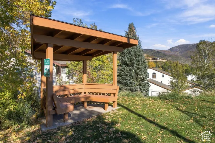 Outdoor timber-frame pavilion featuring integrated bench seating, concrete pad foundation, and mountain backdrop